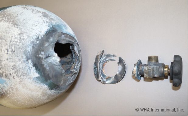 Photo of a fire-damaged oxygen cylinder, neck ring, and cylinder valve after an oxygen cylinder filling system fire